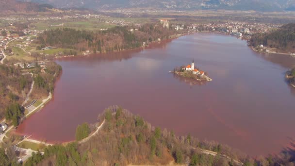 DRONE: Voando acima do famoso lago Bled na Eslovênia cercado por água vermelha . — Vídeo de Stock