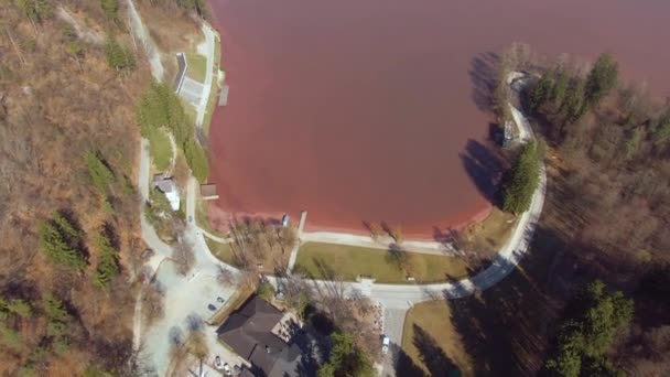 DRONE: Voando acima da estrada vazia correndo em torno de um lago cheio de água vermelha . — Vídeo de Stock