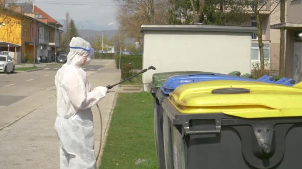 CLOSE UP: Person in hazmat suit sprays garbage bins with antiviral chemicals. — Stock Video