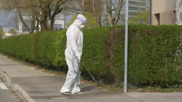 SLOW MOTION Virolog desinficerar trottoaren och lampan vid utbrott av covid-19 — Stockvideo