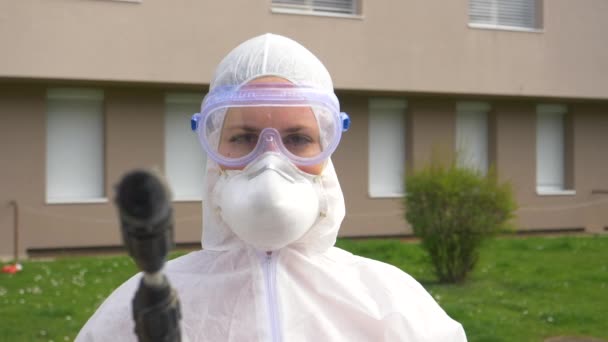 PORTRAIT: Woman in a protective suit sterilizes area during covid-19 epidemic. — Stock Video