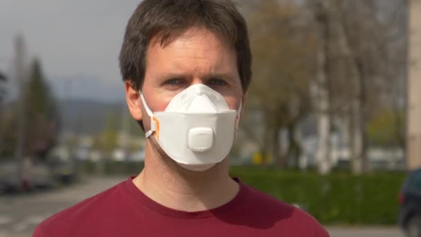 PORTRAIT: Man wearing face mask during covid-19 outbreak wearily looks at camera — Stock Video