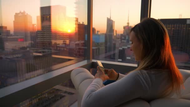 CERRAR: Chica mira su teléfono inteligente desde su oficina con vistas a Times Square. — Vídeo de stock