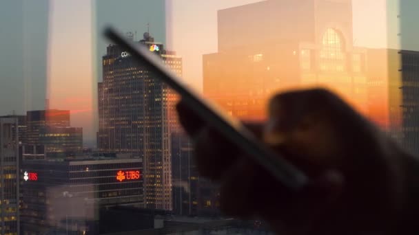 CLOSE UP: Scenisk bild av skyskrapor belysta av solnedgången som kvinna texter. — Stockvideo