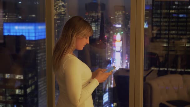 Κοντινό πλάνο: Γυναίκα τουρίστρια γραπτών μηνυμάτων φίλους από το δωμάτιο του ξενοδοχείου της πάνω από Times Square. — Αρχείο Βίντεο
