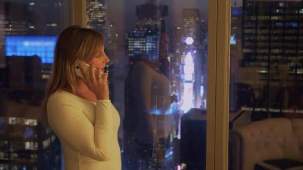 CLOSE UP: Young businesswoman talking on the phone while watching Times Square. — Stock Video