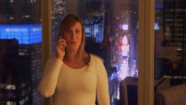 PORTRAIT Girl volá domů v noci z hotelového pokoje nad bzučícími ulicemi NYC — Stock video