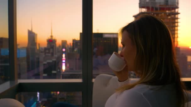 CLOSE UP: Golden Sunrise lyser upp staden som kvinnlig turist dricker sitt kaffe. — Stockvideo