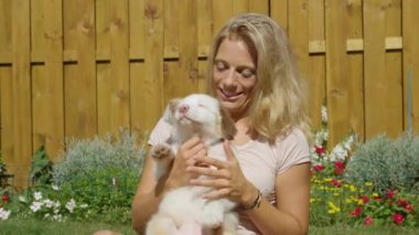 İnatçı beyaz köpek yavrusu güzel bir kadının kucağından kurtulmaya çalışıyor..