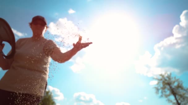 CLOSE UP, DOF: Onherkenbare vrouwelijke boer zaait tarwe op een zonnige zomerdag. — Stockvideo