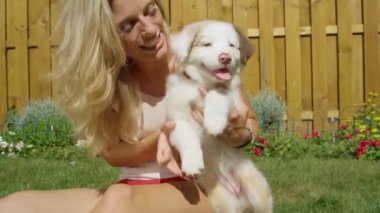 Neşeli kadın güneşli bir günde sevimli pofuduk köpekle bağ kuruyor..
