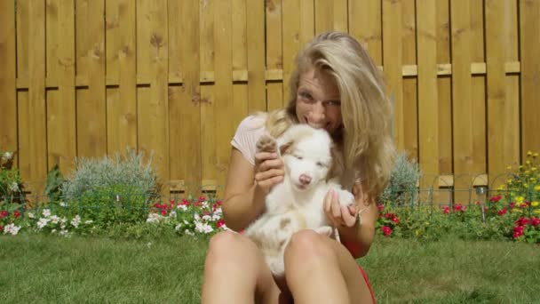 PORTRAIT: Glimlachend meisje neemt de poot en de golven van de lieve puppy 's mee naar de camera. — Stockvideo