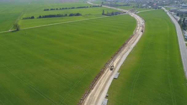 AERIAL: Camino de asfalto conduce desde la ciudad y a lo largo de un oleoducto en construcción — Vídeo de stock
