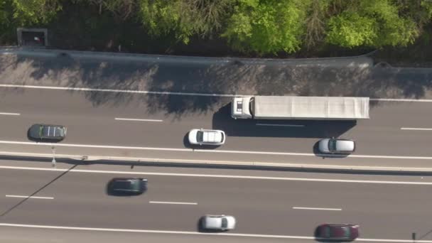 AERIAL: Flyger längs en stor lastbil kör ner upptagen motorväg på en solig dag — Stockvideo