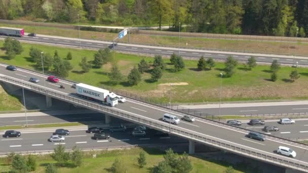 AERIAL: rakománykonténert szállító maerski teherautó áthalad a hídon az autópályán — Stock videók