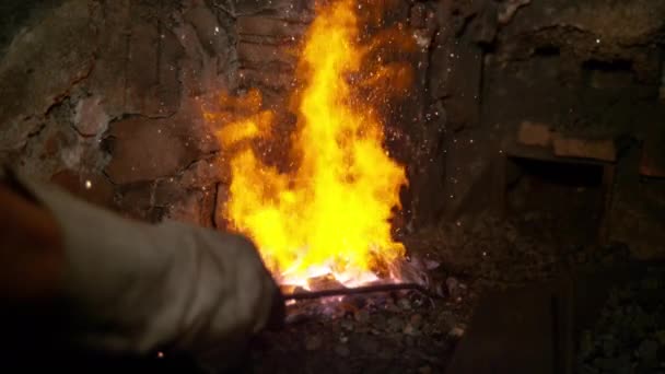 CLOSE UP: Unrecognizable person pokes the fire inside a furnace with a metal rod — Stock Video