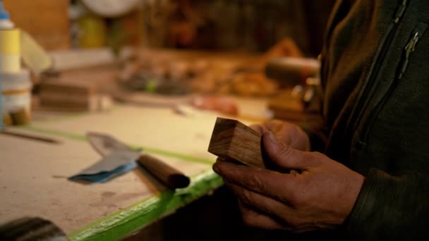 CHIUSURA: Carpentiere seduto accanto alla scrivania e di qualità che ispeziona un pezzo di legno. — Video Stock