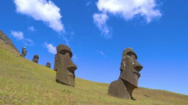 Güzel mavi gökyüzü bir grup eski moai heykelinin üzerinde uzanıyor..