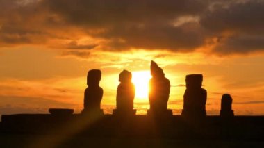 Güneş ışığı: çarpıcı gün batımında moai heykellerinin siluetlerinin çarpıcı görüntüsü.