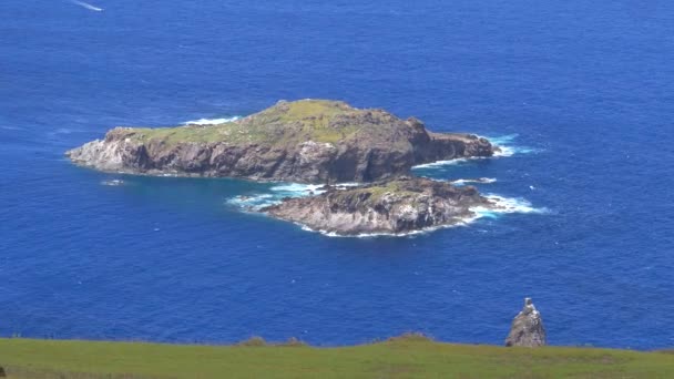 CLOSE UP: Kleine golven drijven langs het oude eilandje Motu Nui op een zonnige dag. — Stockvideo