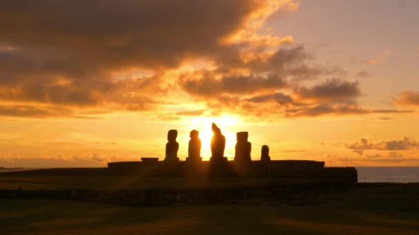Piękne złote promienie słońca świecą na rząd rozpadających się starożytnych moai posągów — Wideo stockowe