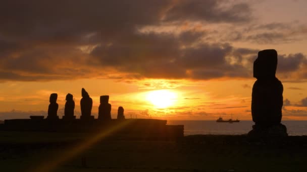 LENS FLARE: Filmový záběr nákladní lodi plující za sochami moai. — Stock video