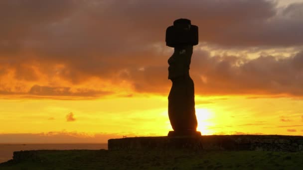 SILHOUETTE: Nubes oscuras se reúnen por encima de la histórica estatua de Moai junto a la orilla. — Vídeos de Stock