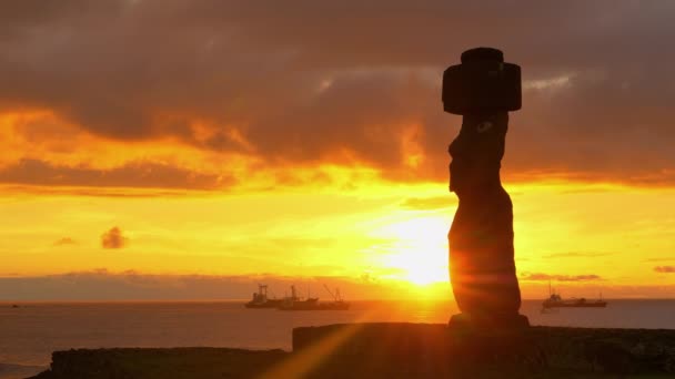 AERIAL: El atardecer del verano ilumina el océano tranquilo y la estatua grande del moai — Vídeo de stock