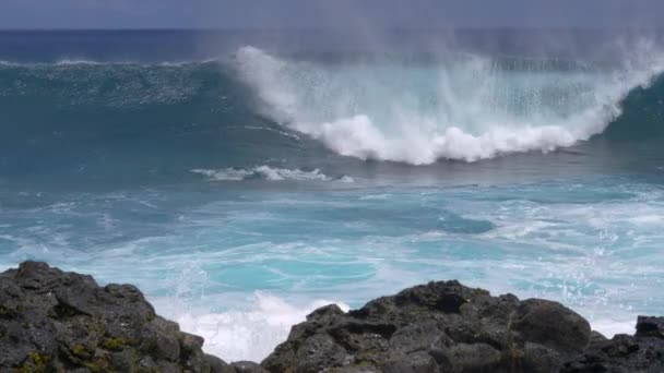SLOW MOTION: Vlny blížící se k sopečnému ostrovu narazí na skalnatý břeh. — Stock video