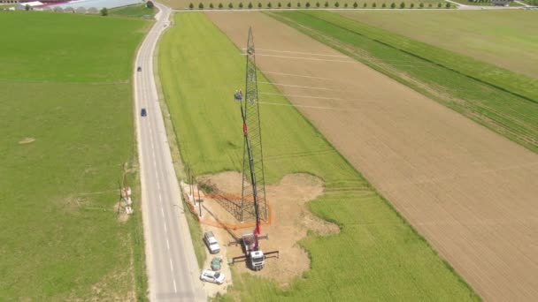 DRONE: Equipe di manutenzione che lavora su un traliccio elettrico vicino alla strada asfaltata. — Video Stock