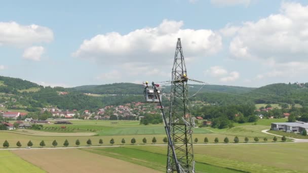 DRONE: Rondvliegend met een groep elektriciens die draden bevestigen aan een hoge pyloon. — Stockvideo