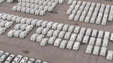 Beyaz kağıda sarılı sayısız araba büyük bir depolama parkına park edilmiş durumda.