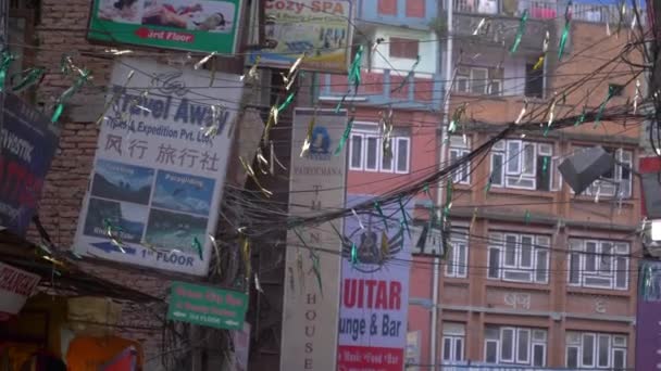 Sluiten omhoog: Kleurrijke vlaggen fladderen in de wind waait langs een straat in Kathmandu — Stockvideo