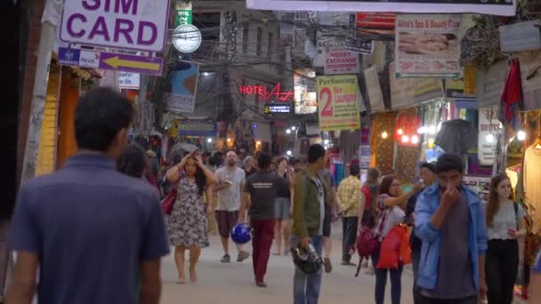LOSE UP: Folk går upp och ner för en livlig gata i Katmandu på kvällen. — Stockvideo