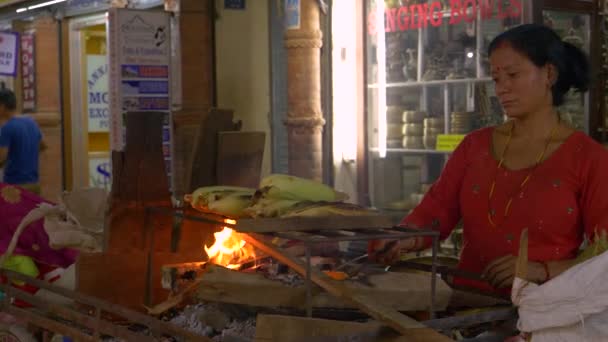 Близко: Местная женщина из Непала жарит кукурузу на открытом огне ночью . — стоковое видео