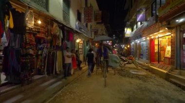 Yerel halk Katmandu 'daki turistlerin önünden bisikletle geçiyor ve yürüyor.