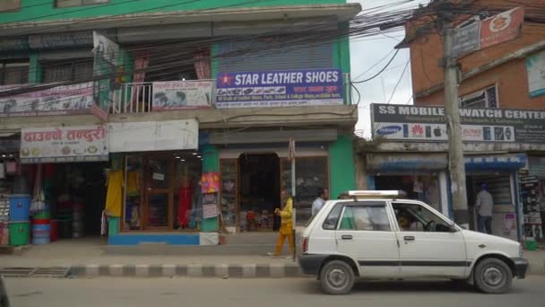 SLOW MOTION: Przejazd obok sklepów turystycznych z widokiem na zatłoczone drogi w Katmandu. — Wideo stockowe