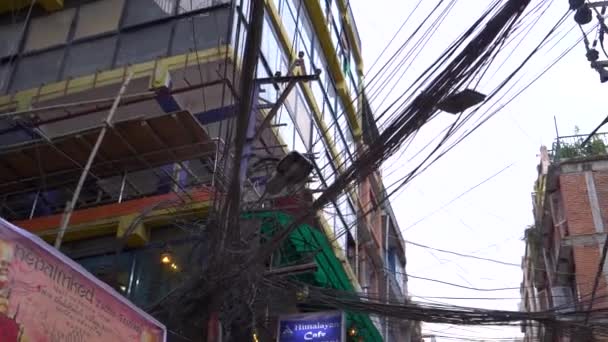 CLOSE UP: Chaotische draden lopen van het ene gebouw naar het andere en boven een straat. — Stockvideo