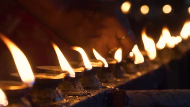 Sluiten omhoog: Kleine vlammen flikkeren als hindoes komen naar een tempel voor een offer. — Stockvideo