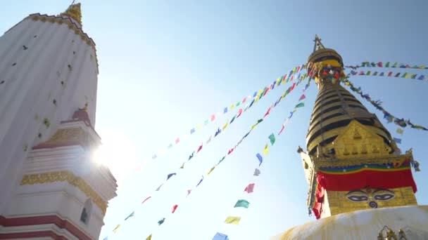 LENS FLARE: Colorful prayer flags flutter in the wind blowing over Monkey Temple — Stock Video