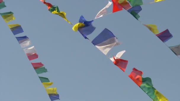 Sluiten omhoog: Veelkleurige gebedsvlaggen opknoping van touwen fladderen in de sterke wind — Stockvideo