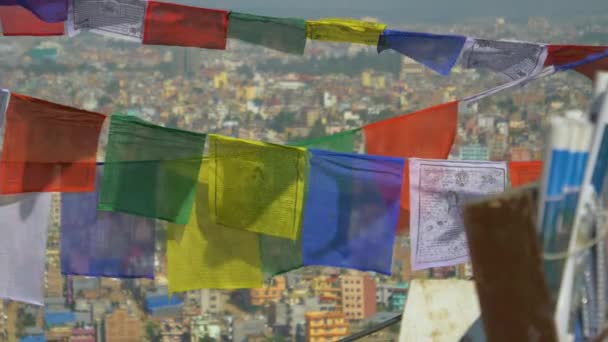 Sluiten omhoog: Kleurrijke gebedsvlaggen fladderen achterin over de stad Kathmandu. — Stockvideo