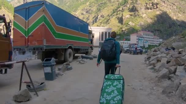 Onherkenbare vrouwelijke toeristische draagtassen langs onverharde weg en voorbij vrachtwagens. — Stockvideo