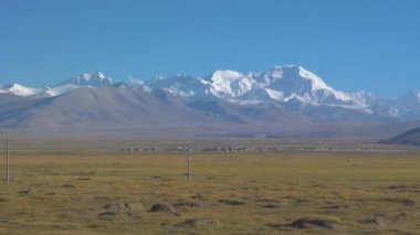 Tibet Platosu 'ndaki bir köyün yanından geçen elektrik hatları boyunca araba sürüyorum.