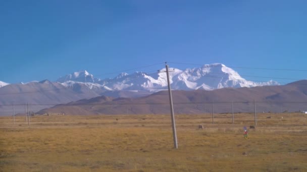 SLOW MOTION: Kraftledningar löper över de stora gröna slätterna på Tibetanska platån — Stockvideo