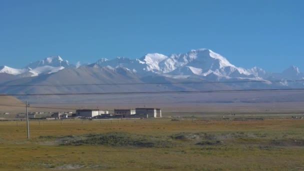 SLOW MOTION: jízda kolem tradičních tibetských domů v rozlehlých zelených pláních. — Stock video