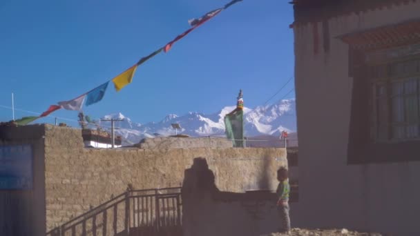 SLOW MOTION: Moving through a rural village in Tibet ornated with prayer flags. — Stock Video