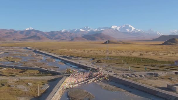 AERIAL: Volando sobre los ríos y carreteras que atraviesan un terreno árido del Tíbet — Vídeos de Stock