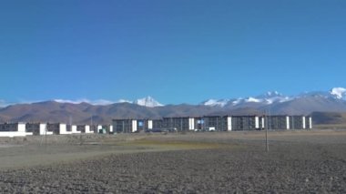 Tibet 'in küçük kasabasına tepeden bakan muhteşem karlı dağ sırası.