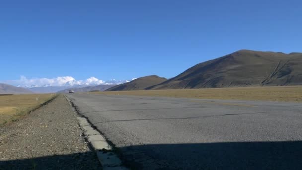 LOW ANGLE: Old truck drives down an empty road running towards Mount Everest. — Stock Video
